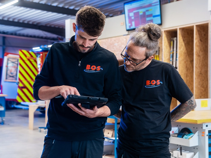 Zwei Mitarbeiter von BOS schauen auf ein Tablet
